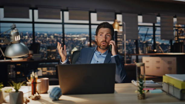 Businessman in modern office discussing business licenses in Dubai over the phone.