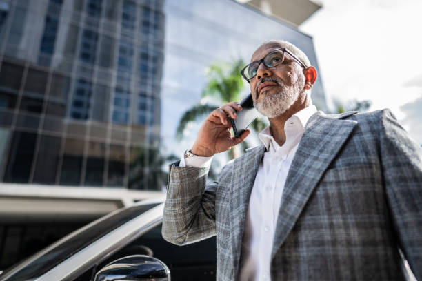 A businessman in a suit talking on the phone in front of a modern building in Dubai.