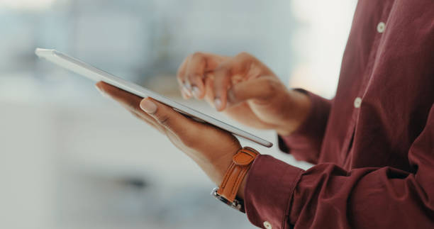 A person in a maroon shirt uses a tablet, possibly researching business licenses in Dubai.