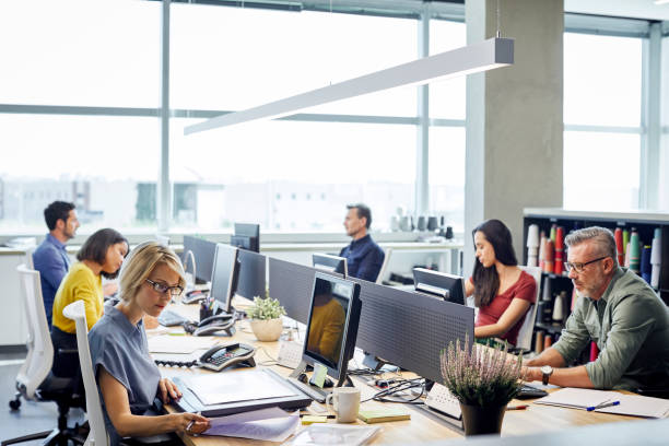 People working on computers in a modern office, representing a bustling IT company environment.