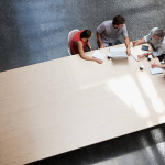 A group of people at a large table discussing business documents in an office setting.